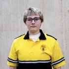 Person wearing glasses and gold and black polo with DPS badge on shirt
