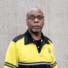 Person wearing glasses and gold and black polo with DPS badge on shirt