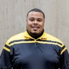 Person wearing gold and black polo top with DPS badge logo