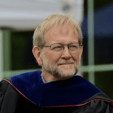 Person wearing glasses and graduation regalia