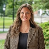 Person wearing jacket and black top and smiling at camera