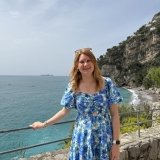 Student standing in front of ocean with large mountain in the background