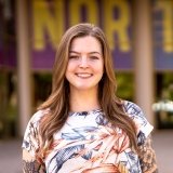 Person wearing multi colored top and smiling at camera
