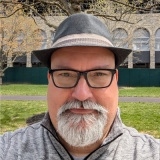 Person wearing fedora and glasses standing in the paddock at Keeneland