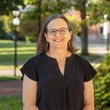 Person wearing glasses and black top smiling at photographer