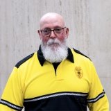 Person wearing glasses and gold and black polo with DPS badge on shirt