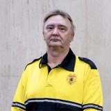 Person wearing gold and black polo top with DPS badge logo