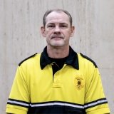 Person wearing gold and black polo top with DPS badge logo