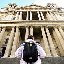 College student wearing black backpack during travel for study abroad