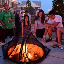Students roasting marshmallows near a dorm