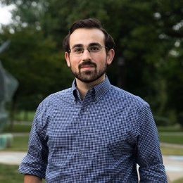 man with dark hair and gotee wearing dark blue gingham dress shirt and glasses