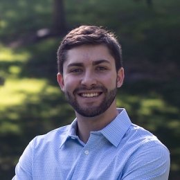 Man with dark brown hair and beard wearing blue button dress shirt