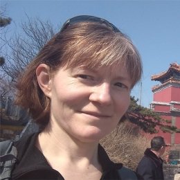 lady with short brunette hair sunglasses on head standing in front of historic building