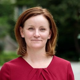 Lady with brunette shoulder link hair wearing red top with gold earrings