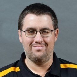 Seth Stogsdill headshot, man with short hair and stubble facial hair wearing black Centre logo athletic polo shirt