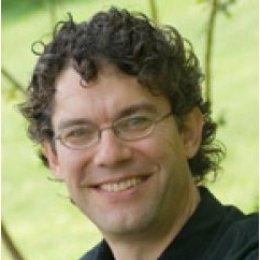 Man with short curly dark hair wearing glasses and black button up shirt