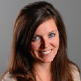 Lady with long dark brown hair with beige top in front of grey background