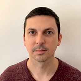 Adam Chen Dedman headshot, man with short dark hair wearing maroon t shirt in front of beige wall