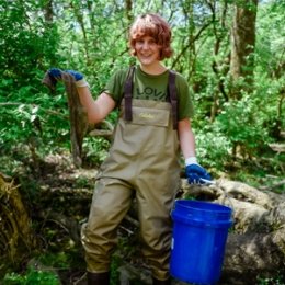 Student cleaning up river