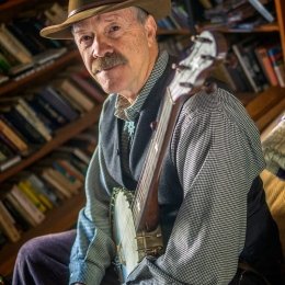 Man with brown hat and mustache holding a banjo