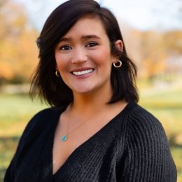 Woman with dark hair wearing a black sweater and necklace