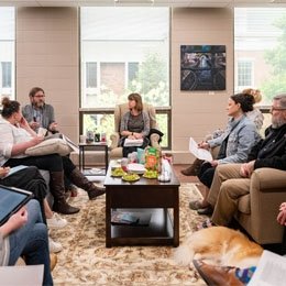 Group of faculty sitting on couches having group discussion