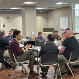 Multiple faculty sitting at tables discussing topics