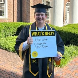 Man holding white board with text American university grad school