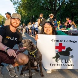 Students holding dog posing with pre-vet society sign