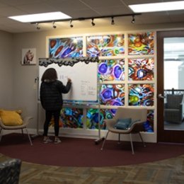 student writing on board inside intercultural suite