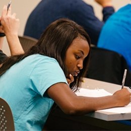 Student writing on paper during class