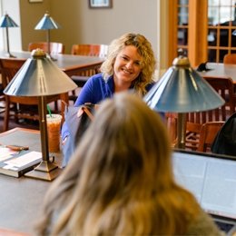 Student talking to another student seated in the library