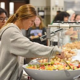 Student selecting fruit from a large bowl