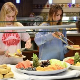 Students picking up cut up fruit at late night breakfast