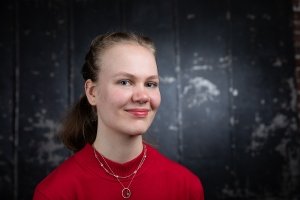 headshot of Uliana wearing red sweater and smiling at camera