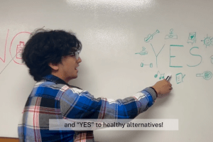 A student points to the word "yes" written on a dry erase board.