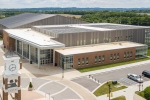 A large building is seen from above with solar panels on the roof and a bell tower is seen in the foreground.