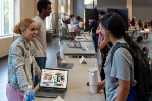 Two women talk across a table while a laptop computer shows photos of one of the women's health care internship.