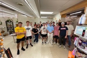 A group of students pose for a photo in a vendor's stall store.