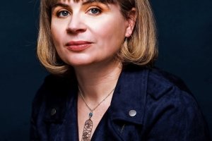 A person with short blond hair poses for a photo.