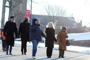 Three women lead a larger group marching along a downtown street.