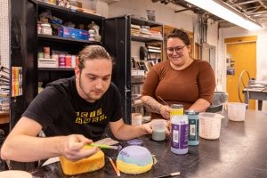 Stephanie Galli watches over Joplin Hora who glazes his bowl.