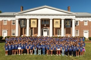 A group photo of the class of 2029. They are all standing in front of Old Centre and wearing bright blue shirts.