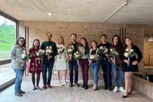 A group of men and women pose for a photo together, each holding a bouquet of flowers.