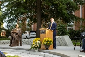 A bronze sculpture of John Marshall Harlan is seen at left while Centre president Milton C. Moreland speaks at a podium.