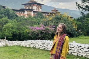 A student studying abroad in Bhutan in front of an historic building in the country.