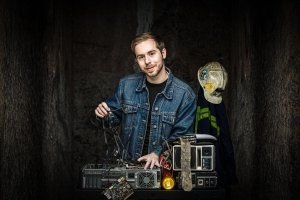 Tyler Kinney ripping wires out of a PC. He looks to be in a cave with a coal miner's helmet in the background.