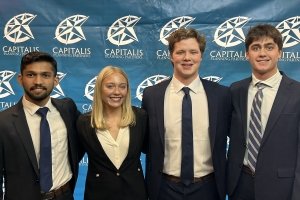 Four students, three men and one woman, wearing business attire, pose for a photo after winning the regional CFA Challenge in Louisville, Kentucky.