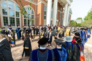 Centre graduates process between faculty lining their path in front of Grace Doherty library.