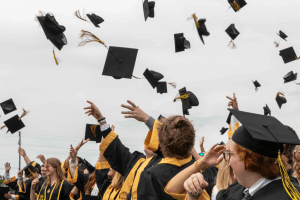 A close up of graduates throwing their caps into the air at the end of the ceremony.